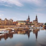 Panoramablick auf Dresden, Deutschland, mit historischen Gebäuden und Booten entlang der Elbe unter einem klaren Himmel.