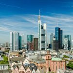 Luftaufnahme der Frankfurter Skyline mit modernen Wolkenkratzern und einem klaren blauen Himmel.