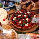 Obsttorte mit verschiedenen Beeren und Sahne im Schaufenster einer Bäckerei.