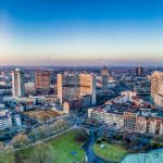 Panoramablick auf die Skyline einer Stadt bei Sonnenuntergang mit modernen Hochhäusern und dichter urbaner Architektur.