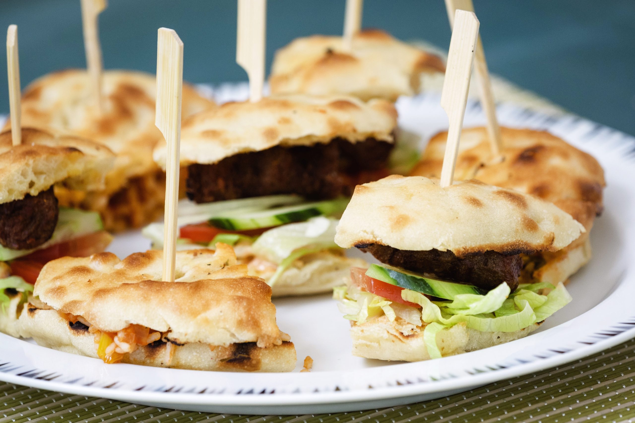 Mini-Sandwiches mit verschiedenen Füllungen auf einem Teller, jeweils mit einem Holzspieß befestigt, eignen sich perfekt für Ihren Betriebsausflug in Bamberg.