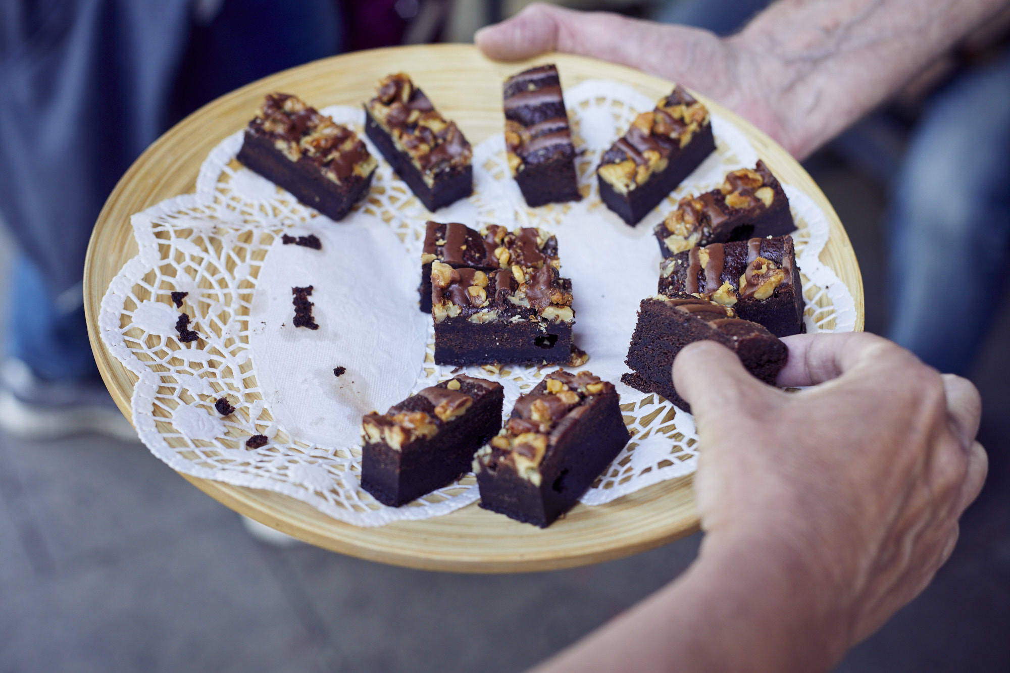 Ein köstlicher Teller mit Schokoladenbrownies, garniert mit Nüssen und einer reichhaltigen Schokoladenglasur, elegant serviert auf einem Deckchen – ein perfekter Leckerbissen nach der Erkundung Bambergs oder während Ihres Betriebsausflugs.