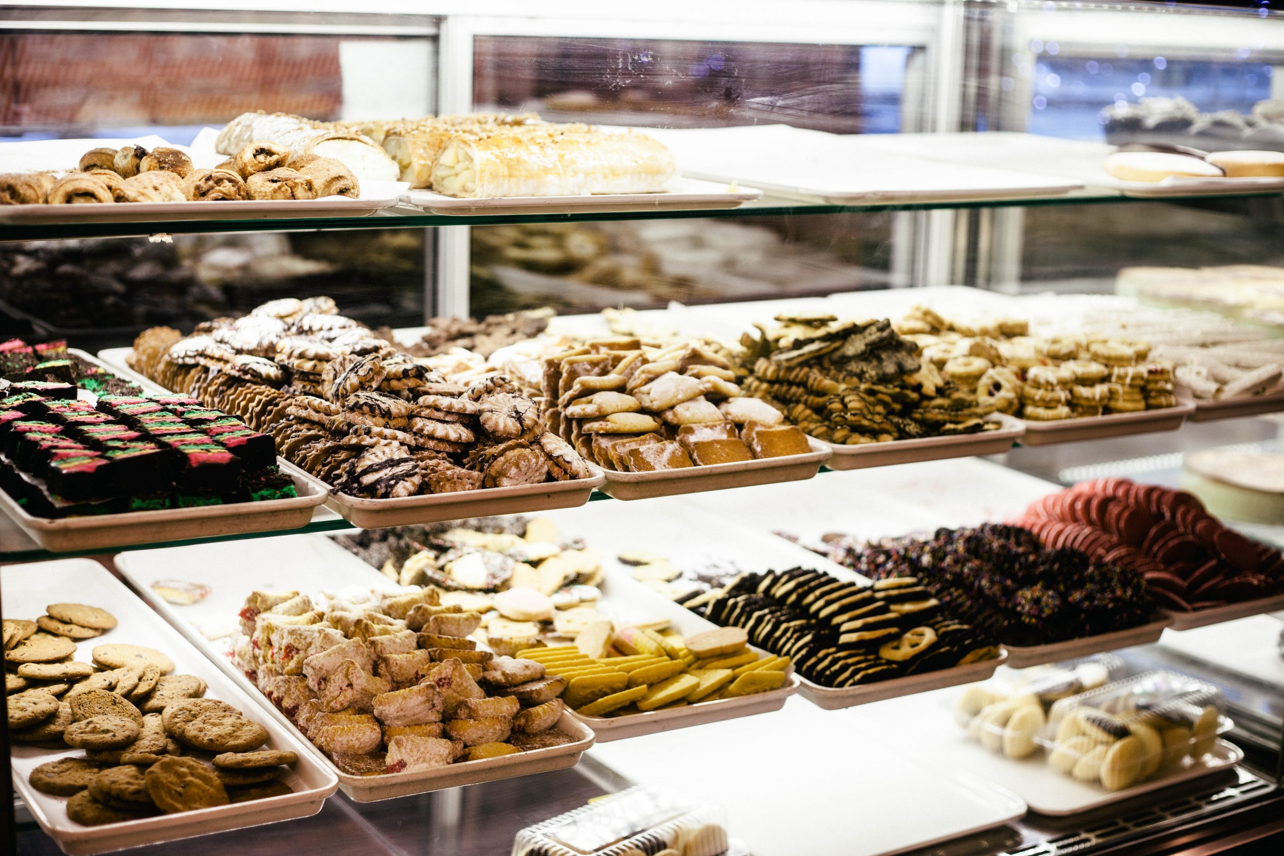 Eine Bäckerei-Vitrine, perfekt für einen Betriebsausflug, präsentiert auf mehreren Regalen verteilt verschiedene Kekse und Gebäcke.