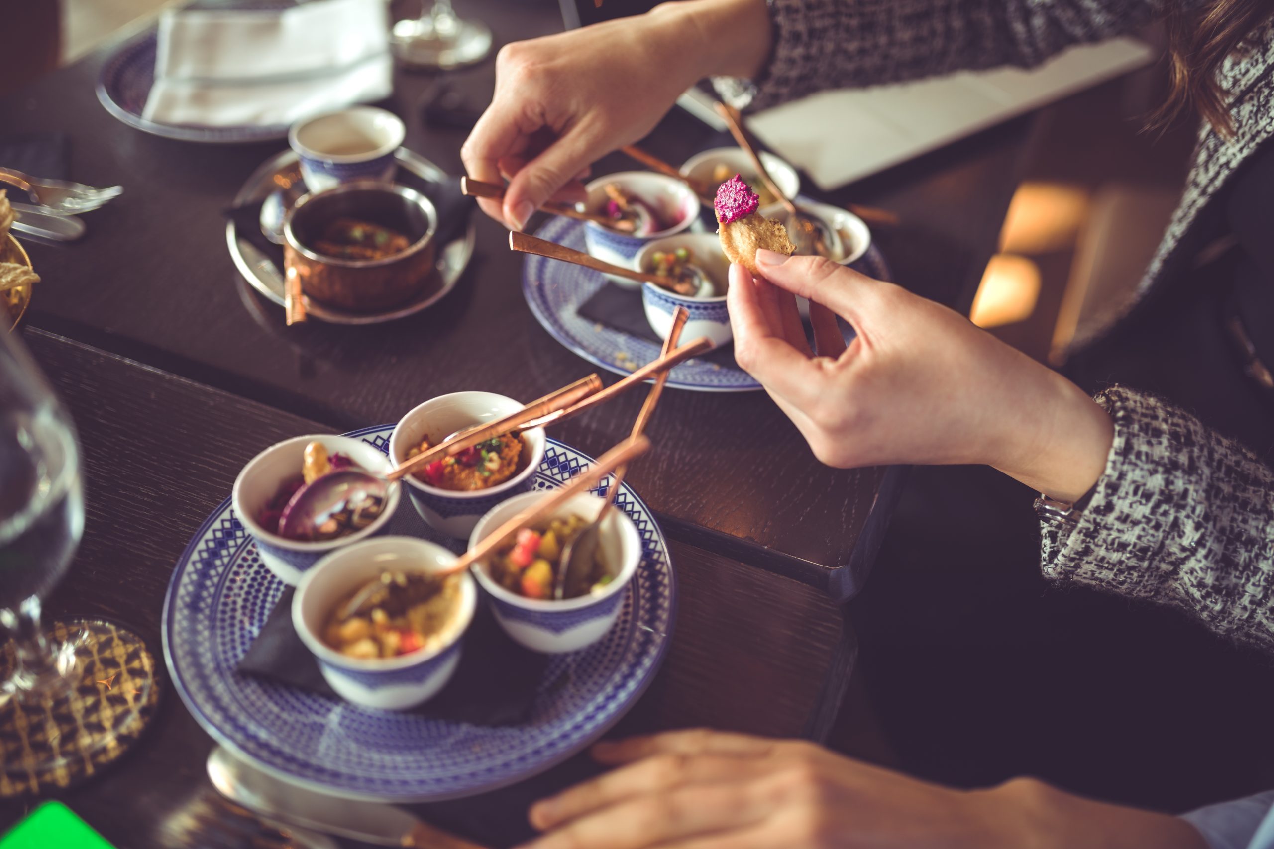 Bei einem genussvollen Betriebsausflug genießt man am Restauranttisch mit Stäbchen eine Vielzahl kleiner Gerichte und genießt jeden Bissen.