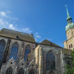 Historische Kirche mit Bogenfenstern und einem hohen Turm unter einem klaren blauen Himmel.