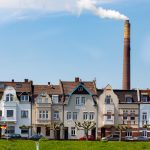 Reihe farbenfroher europäischer Häuser mit Schornstein im Hintergrund unter einem blauen Himmel.