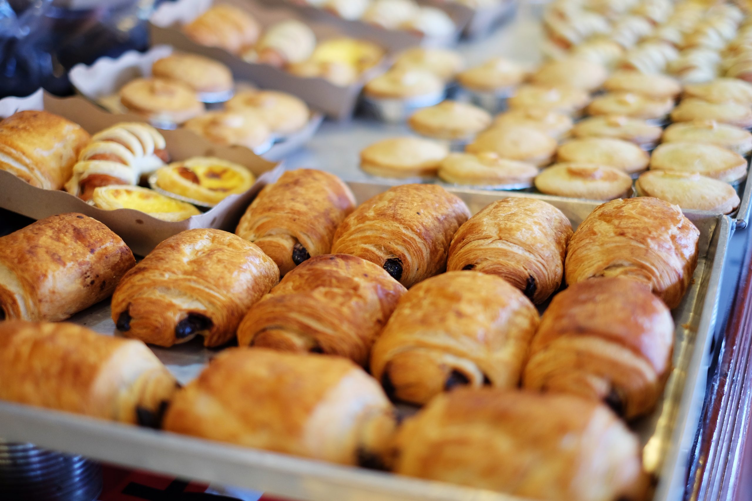 Verschiedene Backwaren, darunter Croissants und Törtchen, werden hübsch auf Tabletts präsentiert und sorgen für ein herrliches Erlebnis der Erlebnisgastronomie.