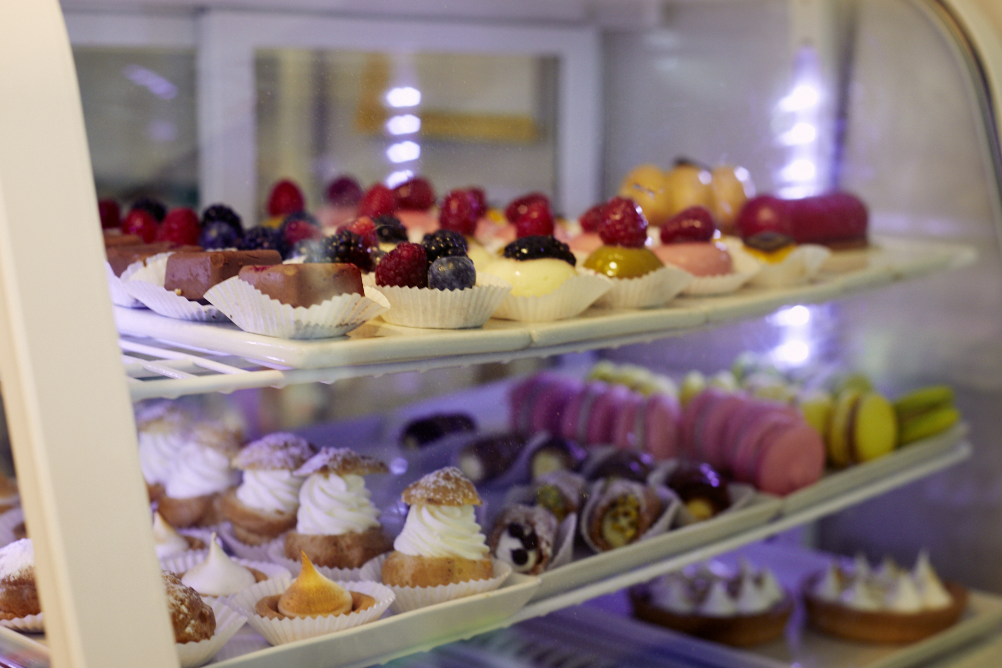 Eine Vitrine gefüllt mit verschiedenen bunten Gebäck- und Dessertsorten, darunter Törtchen, Kuchen und Macarons, macht jeden Besuch zu einem Erlebnisgastronomie-Erlebnis.