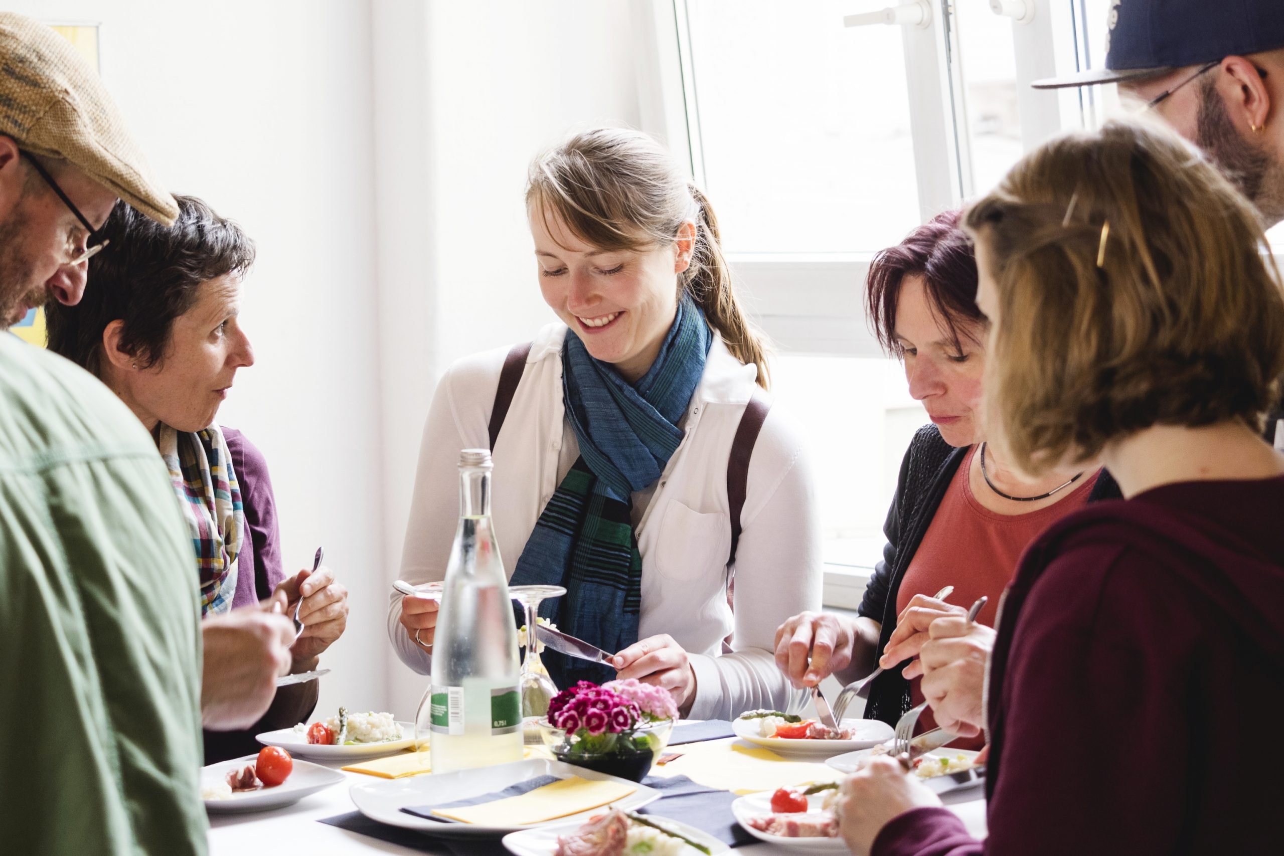 Eine Gruppe von Menschen versammelt sich um einen Tisch, teilt köstliches Essen und Lachen und schafft Erinnerungen, die die perfekte Geschenkidee abgeben.