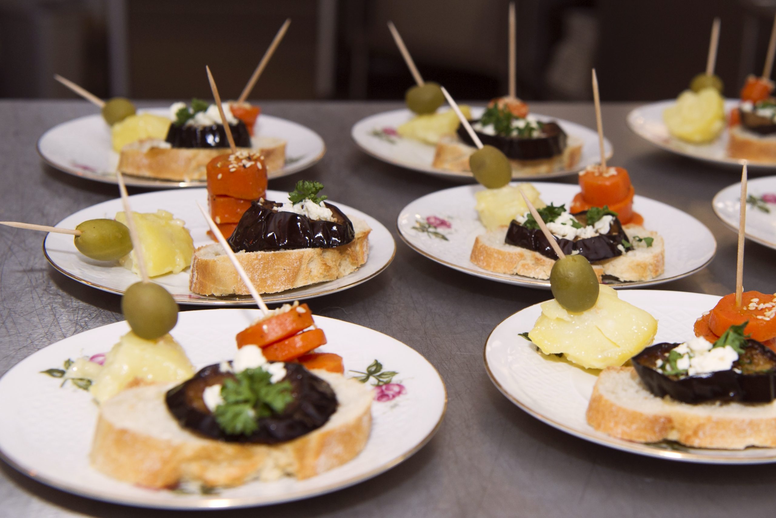 Teller mit geschnittenem Brot, belegt mit gegrillten Auberginen, Käse, Oliven und Gemüsespießen, sind der perfekte Happen bei einer Junggesellenabschiedsfeier.