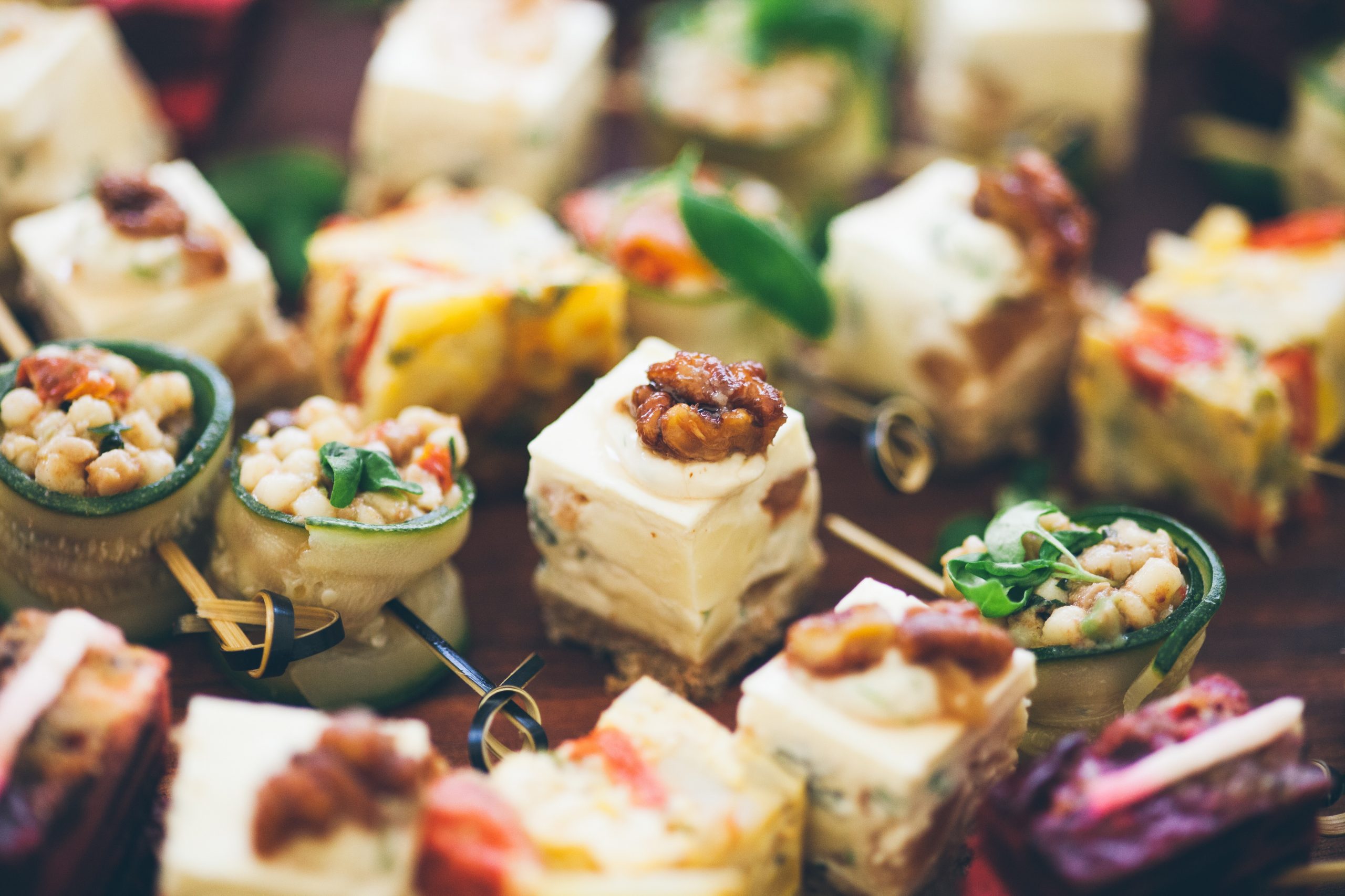 Eine Auswahl farbenfroher Gourmet-Häppchen mit dekorativen Belägen auf einer Holzoberfläche bietet den perfekten Snack-Aufstrich für eine Junggesellenabschiedsfeier.