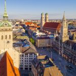 Luftaufnahme des Münchner Marienplatzes mit historischen Gebäuden, darunter das Neue Rathaus und die Frauenkirche.