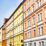 Farbenfrohe Reihe historischer europäischer Gebäude mit kunstvollen Details vor einem klaren blauen Himmel.