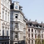 Eine Straßenansicht eleganter, historischer europäischer Gebäude mit reich verzierten Fassaden und einem klaren blauen Himmel.