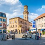 Ein sonniger Stadtplatz in Fürth verfügt über historische Gebäude, einen Uhrenturm und einen Eingang zu einer U-Bahn-Station.