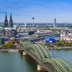 Luftaufnahme von Köln, Deutschland, mit dem Dom, modernen Gebäuden und einer Brücke über den Rhein.