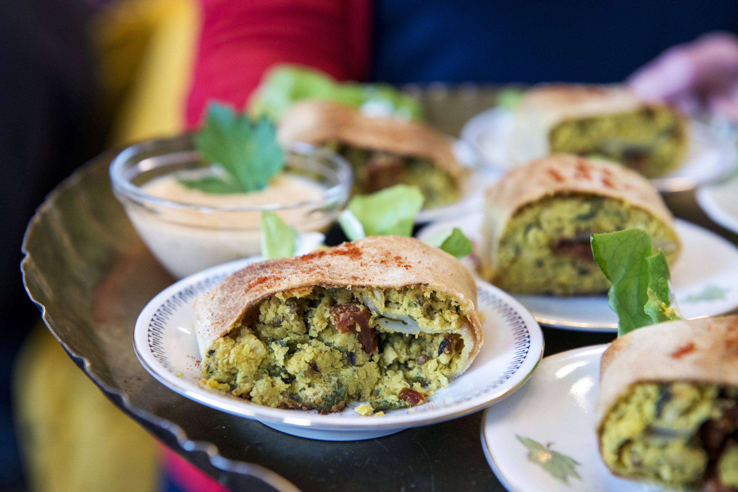 Auf einem Tablett servierte Falafel-Wraps mit Dip-Sauce und Petersilie, perfekt für jede Weihnachtsfeier.