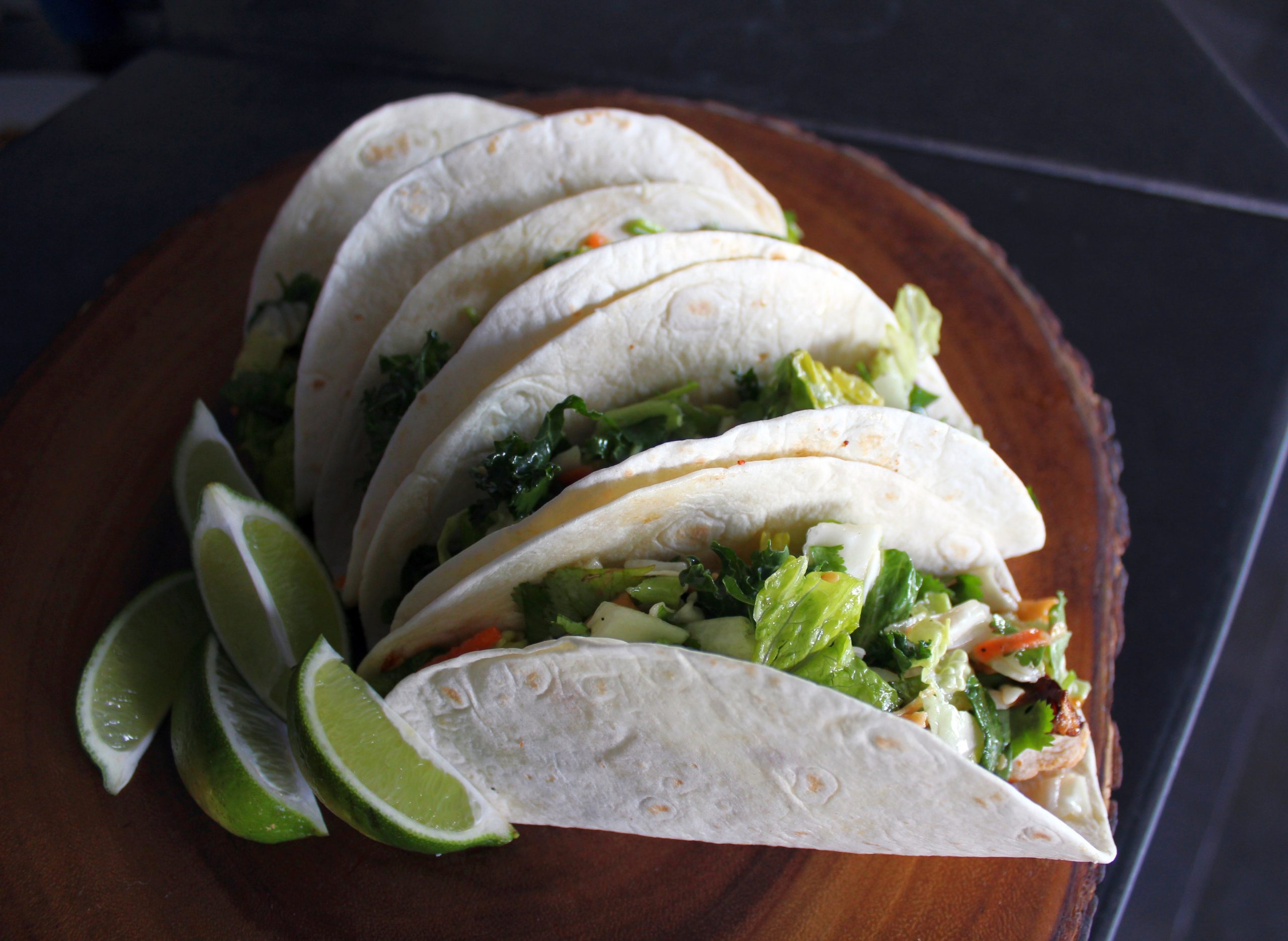 Tacos mit Salat und Limettenspalten auf einem Holzteller sind ein herrlicher Snack während eines Betriebsausflugs.