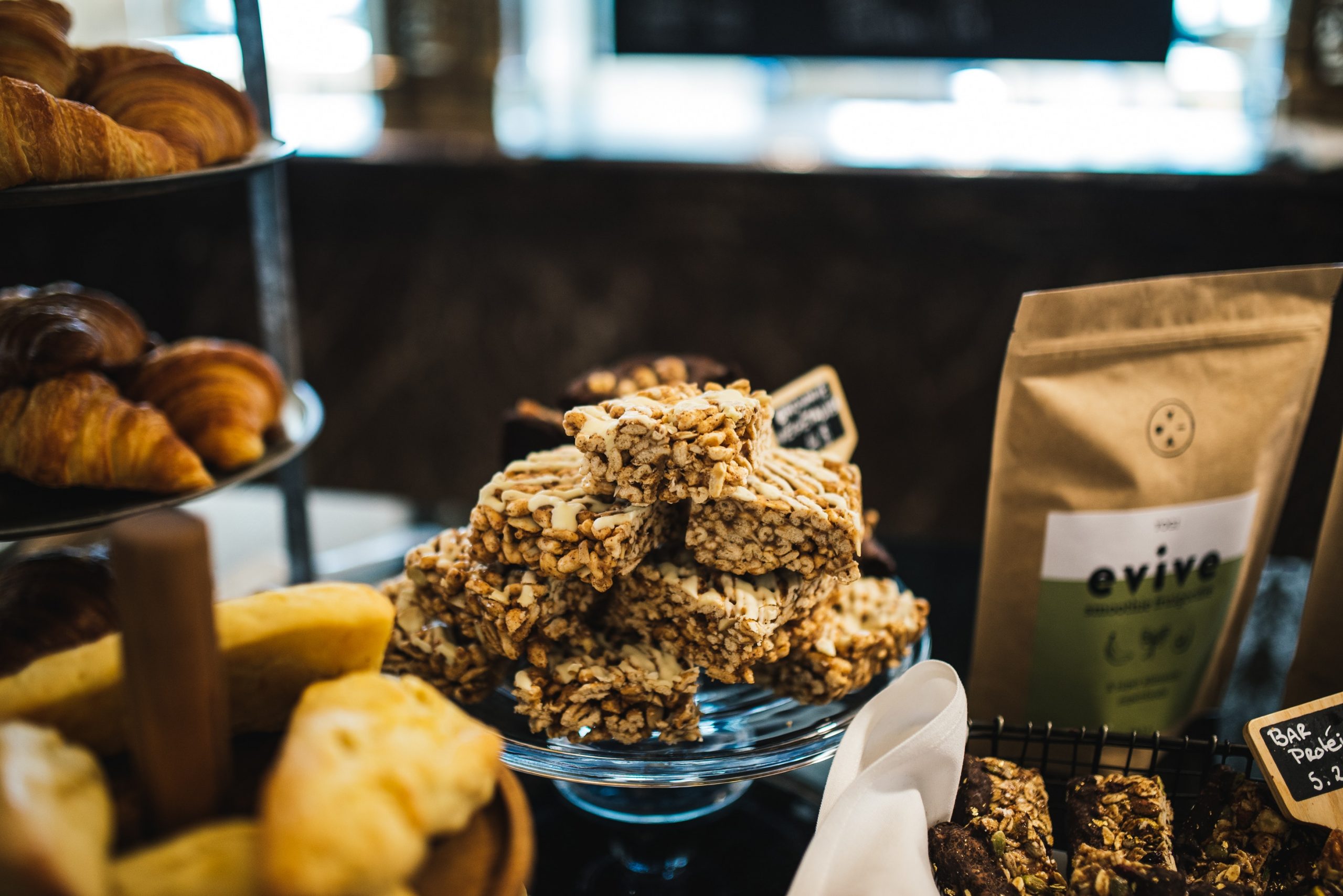 Eine köstliche Auswahl an Müsliriegeln, Croissants und Gebäck ziert den Tisch in diesem gemütlichen Café-Ambiente, perfekt für ein festliches Weihnachtsfeier-Treffen.