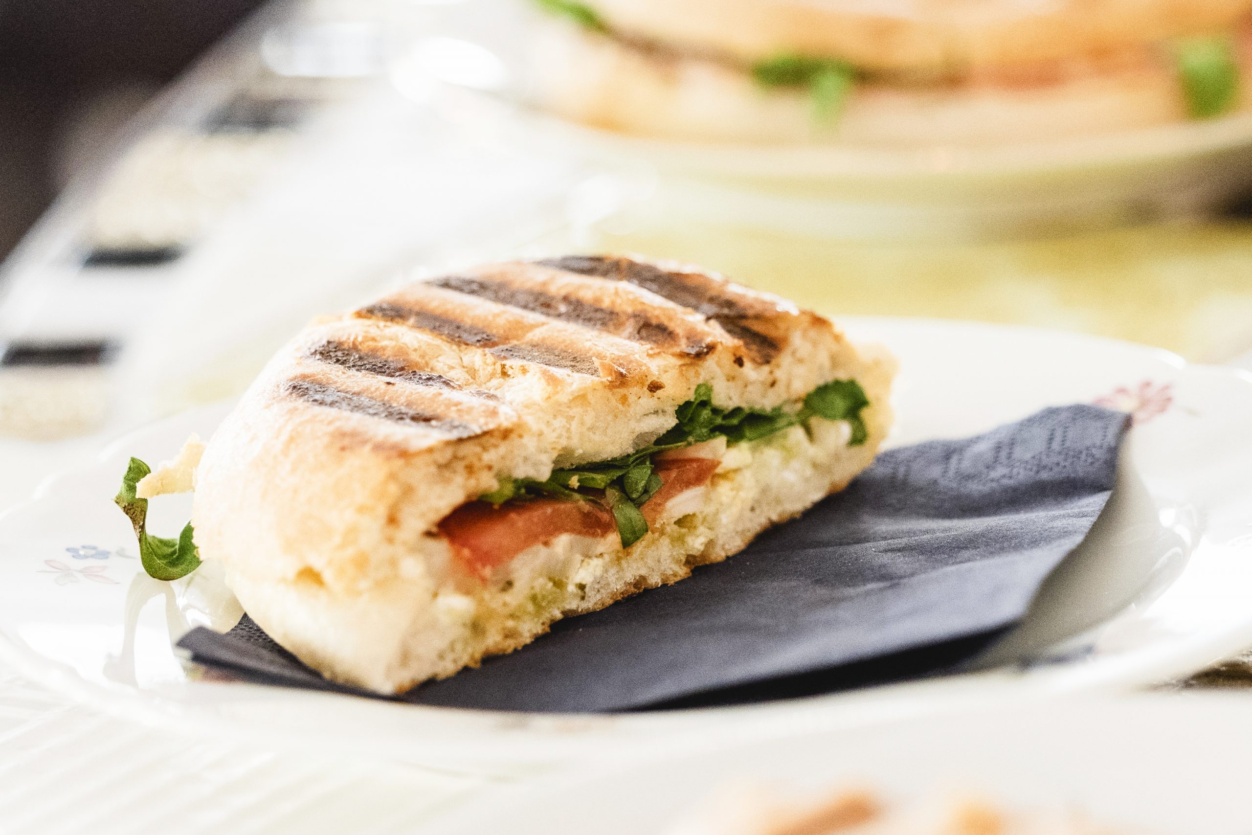 Ein gegrilltes Sandwich mit Salat und Tomaten auf einem Teller mit Serviette ist der perfekte Snack für einen Betriebsausflug.