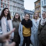 Eine Gruppe lächelnder Menschen in Winterkleidung im Freien in einer Stadt.