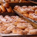 Reihen von mit Zucker überzogenem Gebäck und Donuts mit Marmeladefüllung, perfekt für jede Weihnachtsfeier, werden in der Bäckerei hübsch auf Tabletts präsentiert.