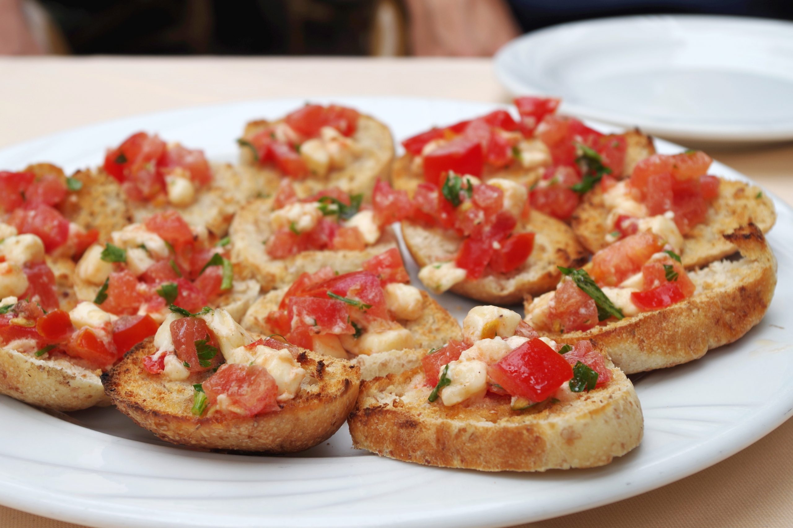 Eine perfekte Vorspeise für einen Junggesellenabschied: Dieser Teller Bruschetta ist mit gewürfelten Tomaten, Käse und Kräutern auf geröstetem Brot belegt.