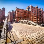 Historische rote Backsteingebäude und eine Kanalbrücke an einem sonnigen Tag in der Hamburger Speicherstadt.