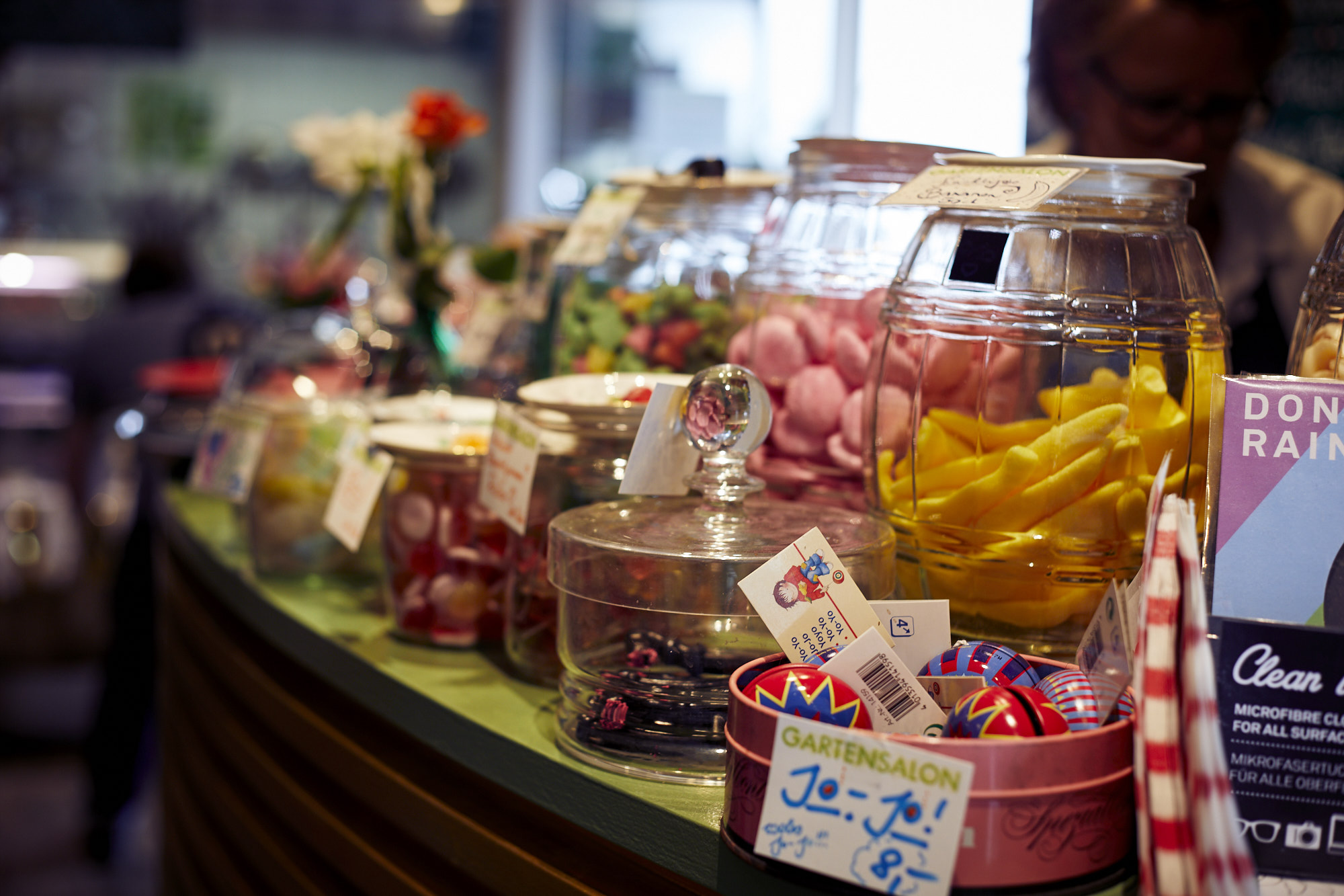 Verschiedene Süßigkeiten in Gläsern werden auf einer bunt dekorierten Theke präsentiert und erzeugen so eine Atmosphäre der Erlebnisgastronomie, die zu einem köstlichen Sinneserlebnis einlädt.