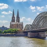 Kölner Dom und Hohenzollernbrücke über den Rhein an einem sonnigen Tag mit einigen Wolken.