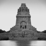 Das Denkmal, ein Höhepunkt jeder historischen Tour, ist von Wasser umgeben und verfügt über komplizierte Skulpturen und eine hoch aufragende Struktur, die sich vor dem klaren Himmel Leipzigs abhebt.