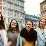 Eine Gruppe von Menschen macht eine Pause von ihrer Büroarbeit und lächelt auf einer belebten Stadtstraße. Bunte Gebäude bilden die perfekte Kulisse.