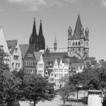 Schwarzweißfoto einer Stadtlandschaft mit historischen Gebäuden und einem Dom mit hohen Türmen, das den Charme der Kölner Altstadt einfängt.