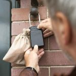 Eine Person schließt einen an einer Ziegelwand befestigten Wandschließkasten auf. In der Nähe befindet sich ein kleiner Leinensack.