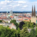 Luftaufnahme von Bielefeld, Deutschland, mit den Türmen der St. Marienkirche, umgeben von Gebäuden und üppigem Grün.