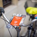 Ein Fahrrad mit einem Reiseführer „Münster Altstadt“ am Lenker, perfekt für eine historische Tour, und einem bunten Spielzeug daran befestigt.