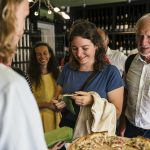 Eine Gruppe von Menschen genießt Pizza bei einem Treffen in einem Weinladen.