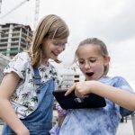 Zwei Kinder im Düsseldorfer Nordpark starren aufgeregt auf ein Tablet. Kräne und Baustellen rahmen ihr Abenteuer ein, das sich wie eine von GEOLINO inspirierte Stadtrallye anfühlt.