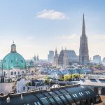 Skyline von Wien mit dem Stephansdom vor der Kulisse historischer Gebäude und klarem blauen Himmel.